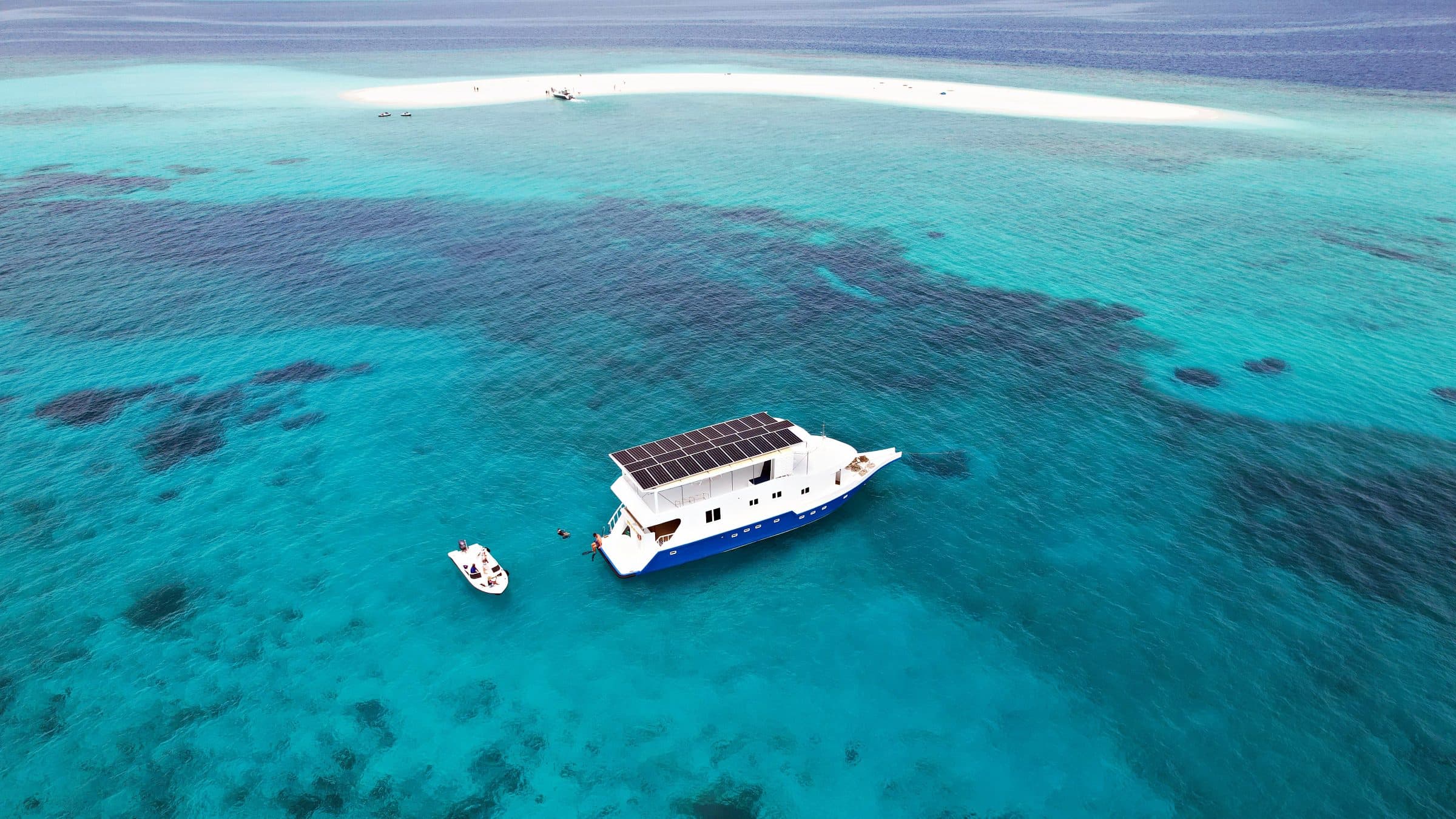 Aerial view of NOAH beside a coral reef and white sandbank