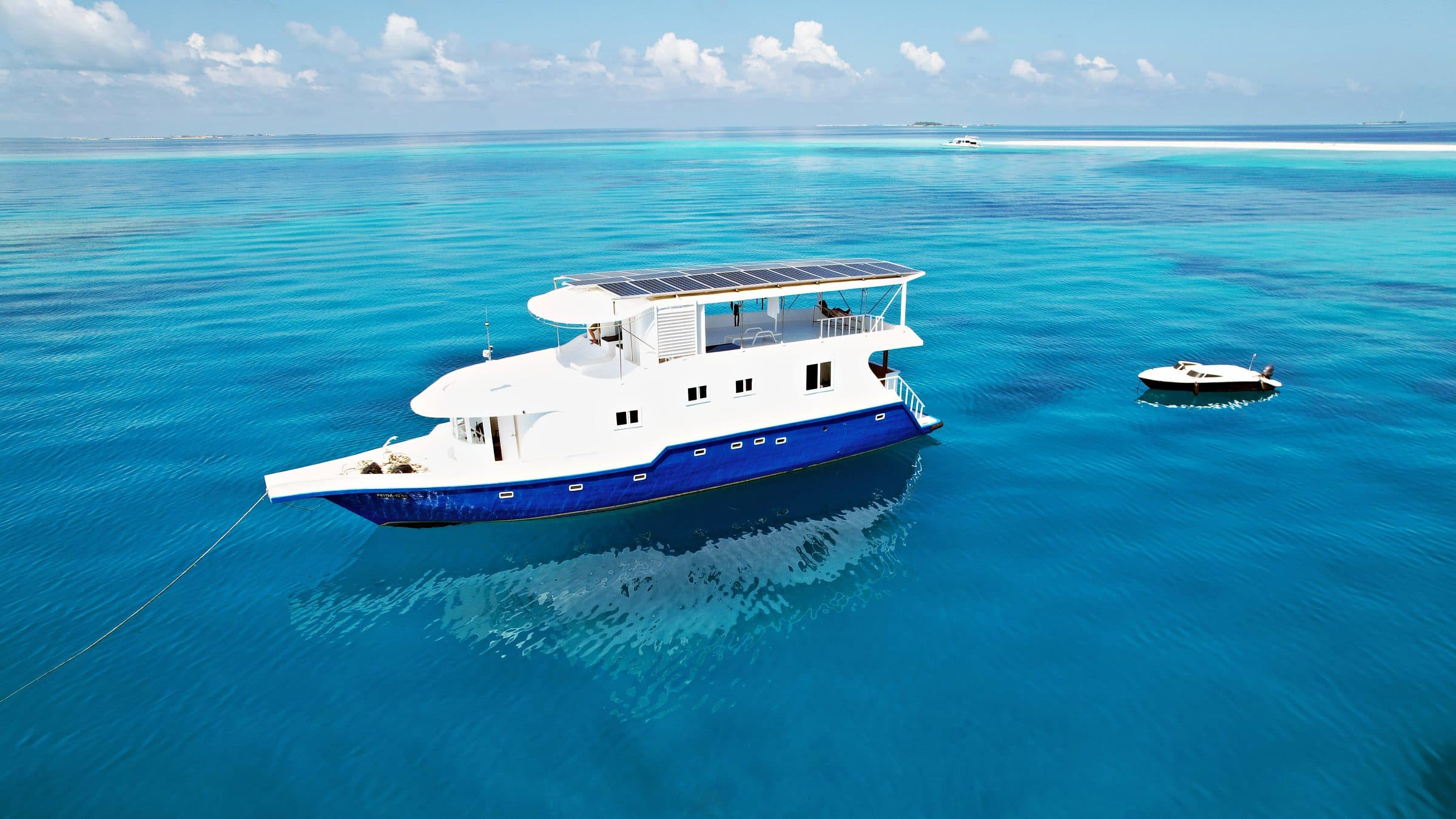 NOAH anchored in a turquoise lagoon with her dinghy